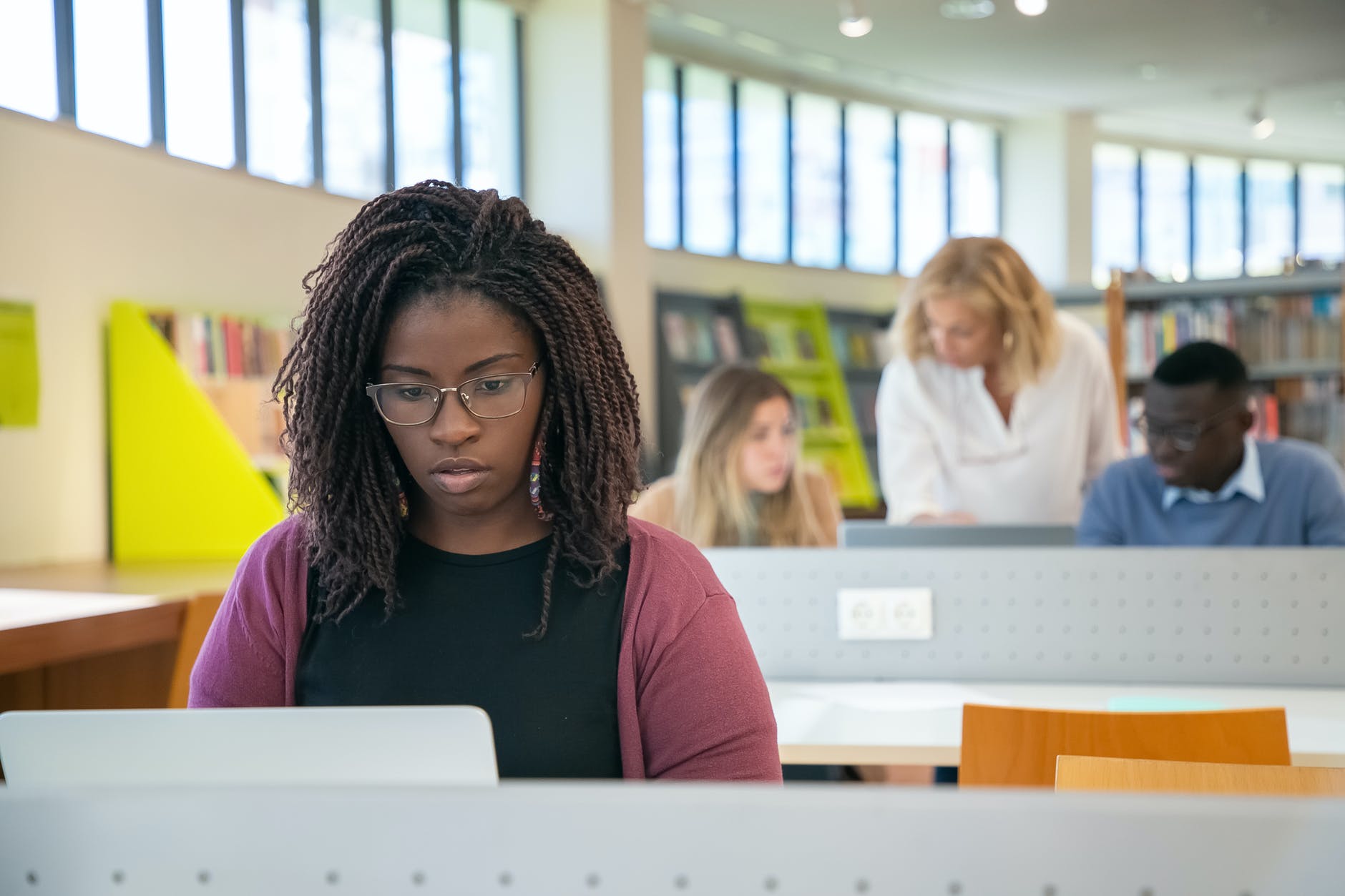 focused multiracial students doing presentation in library with teacher